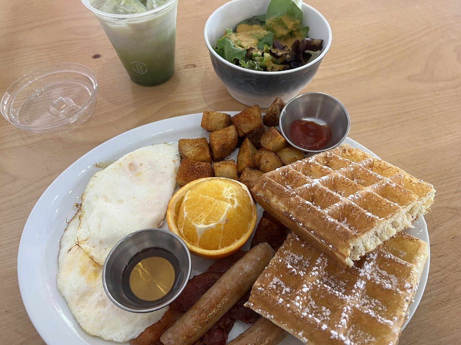 Wonderffle brunch plate with waffle, eggs, sausage, bacon, hash and orange